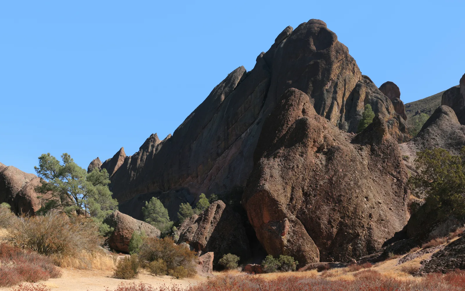 Rocky volcanic spires and formations at Pinnacles National Park with desert vegetation and hiking terrain